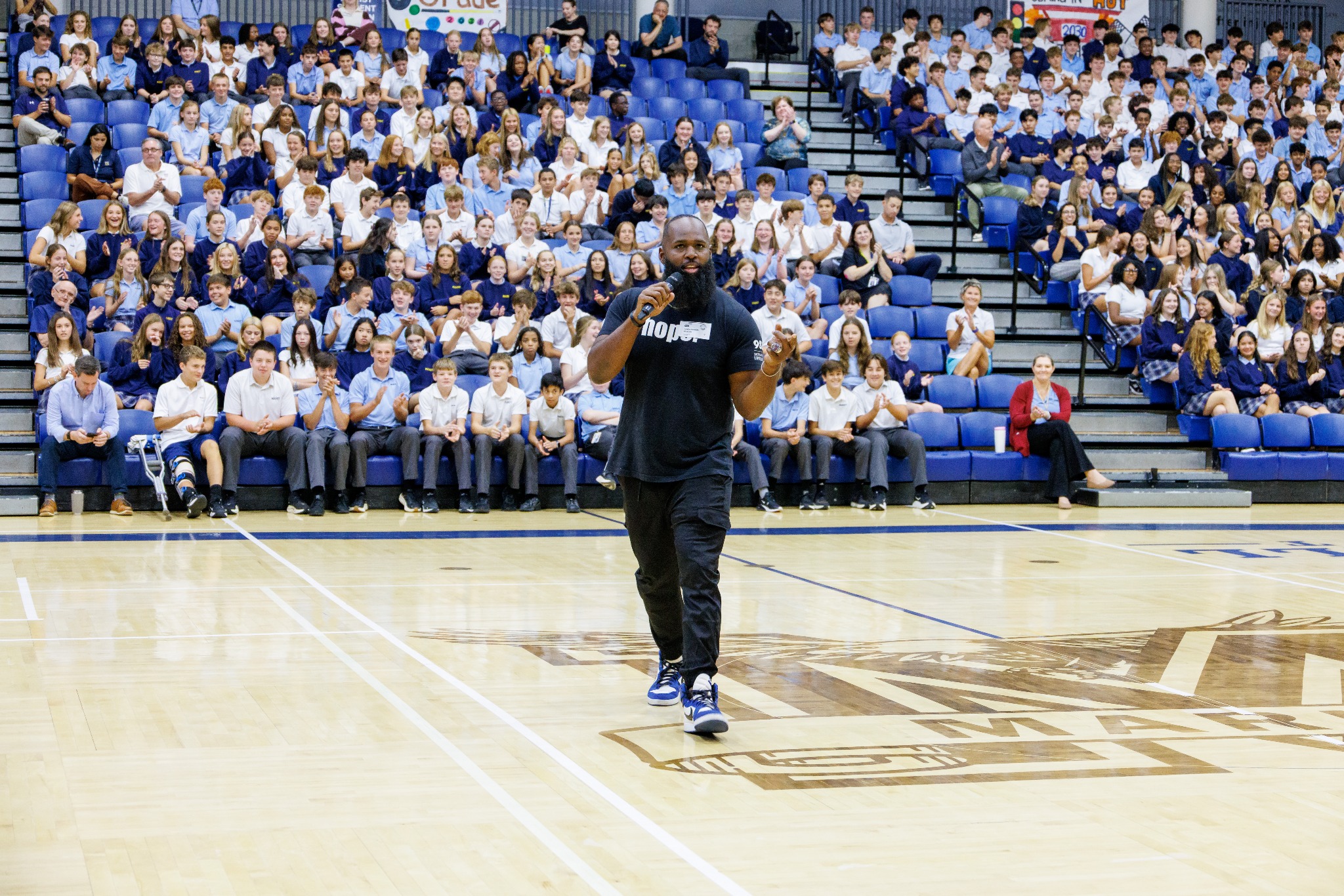 Andre Fluellen speaking to a full school gymnasium