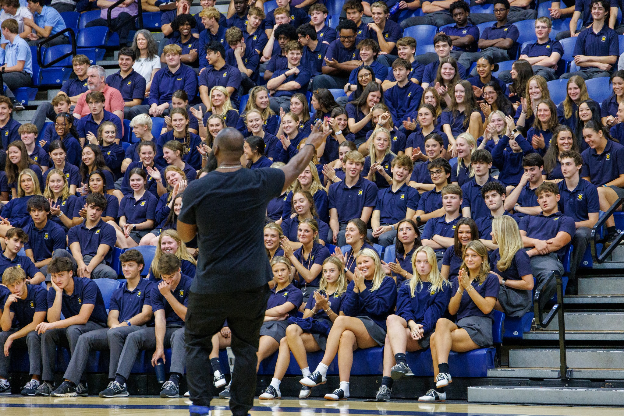 Andre Fluellen speaking to a full school audience from the gym floor