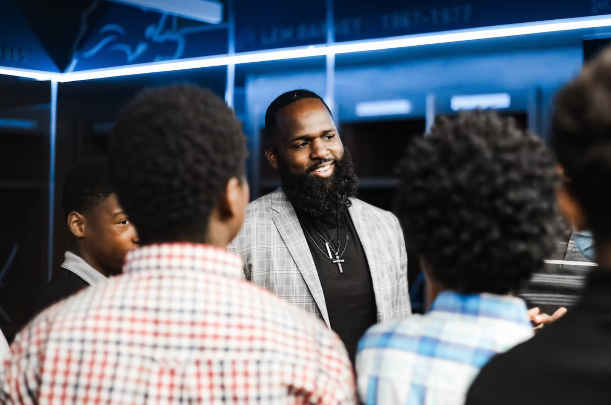 Andre Fluellen in a gray blazer smiling and talking with a group of students